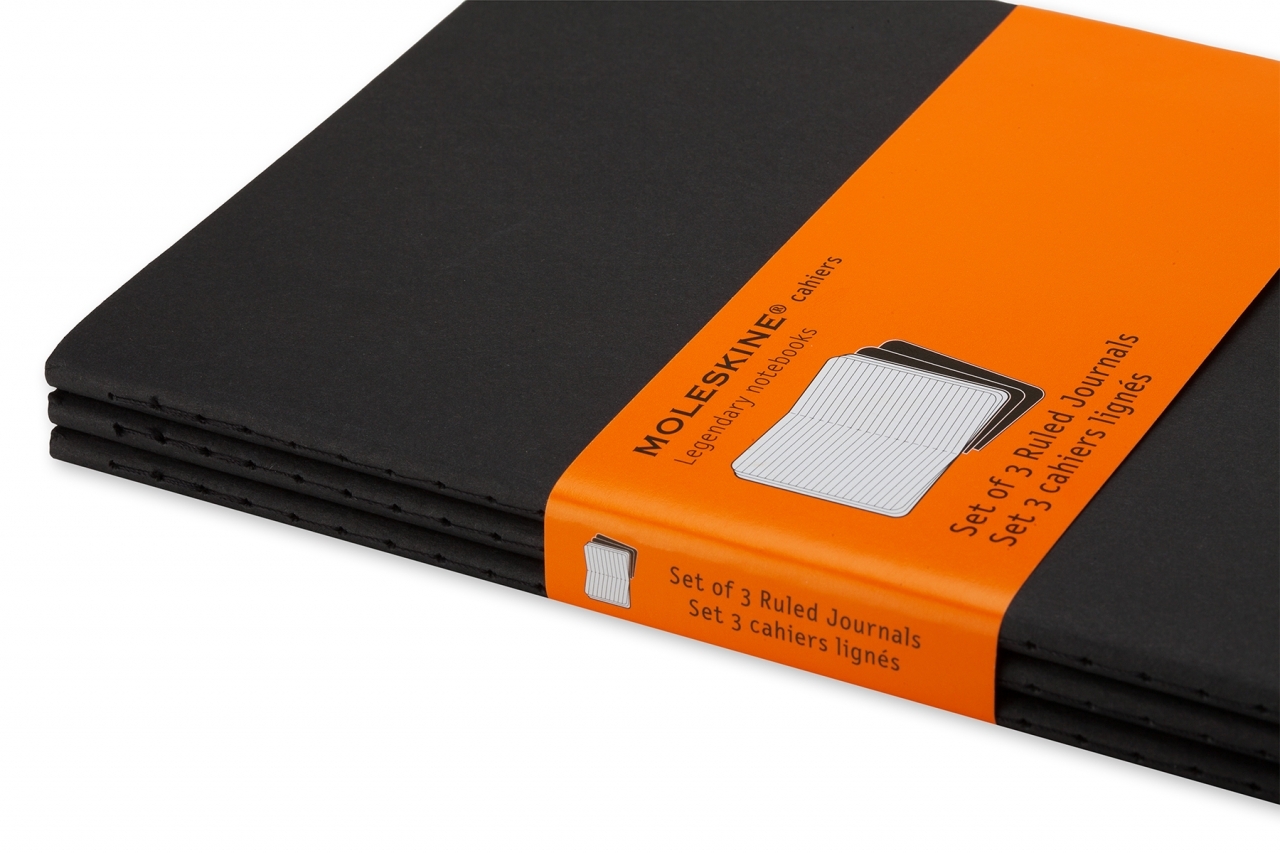Arti parodyta trijų juodų Moleskine Cahier užrašinių krūvelė su oranžine juosta ir linijuotų puslapių piešiniu