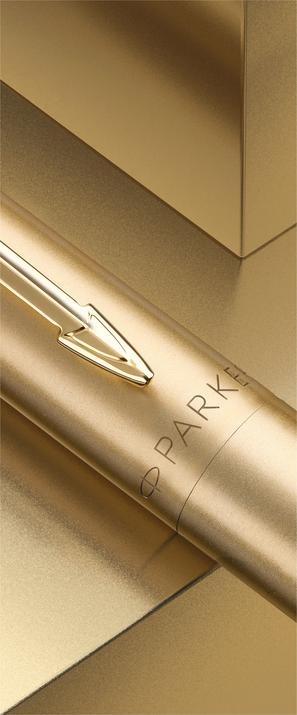 Aukso spalvos Parker Jotter XL tušinuko korpuso detalė su rodyklės spaustuku ir Parker logotipu tarp metalinių plokštumų