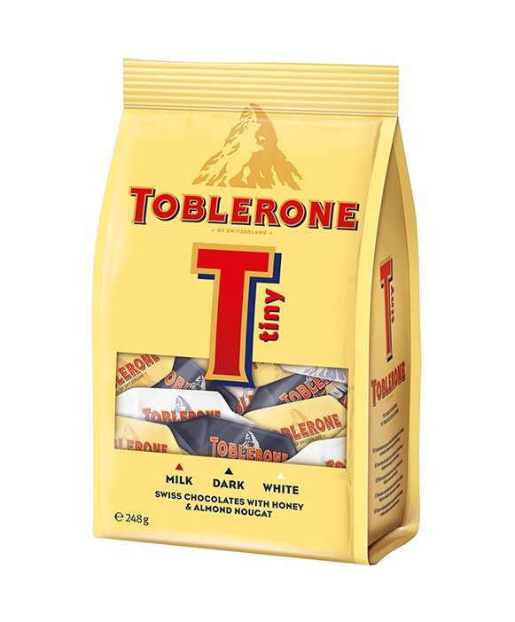 Stačias geltonas Toblerone Tiny maišelis su pieninio, juodojo ir baltojo šokolado saldainiais už langelio