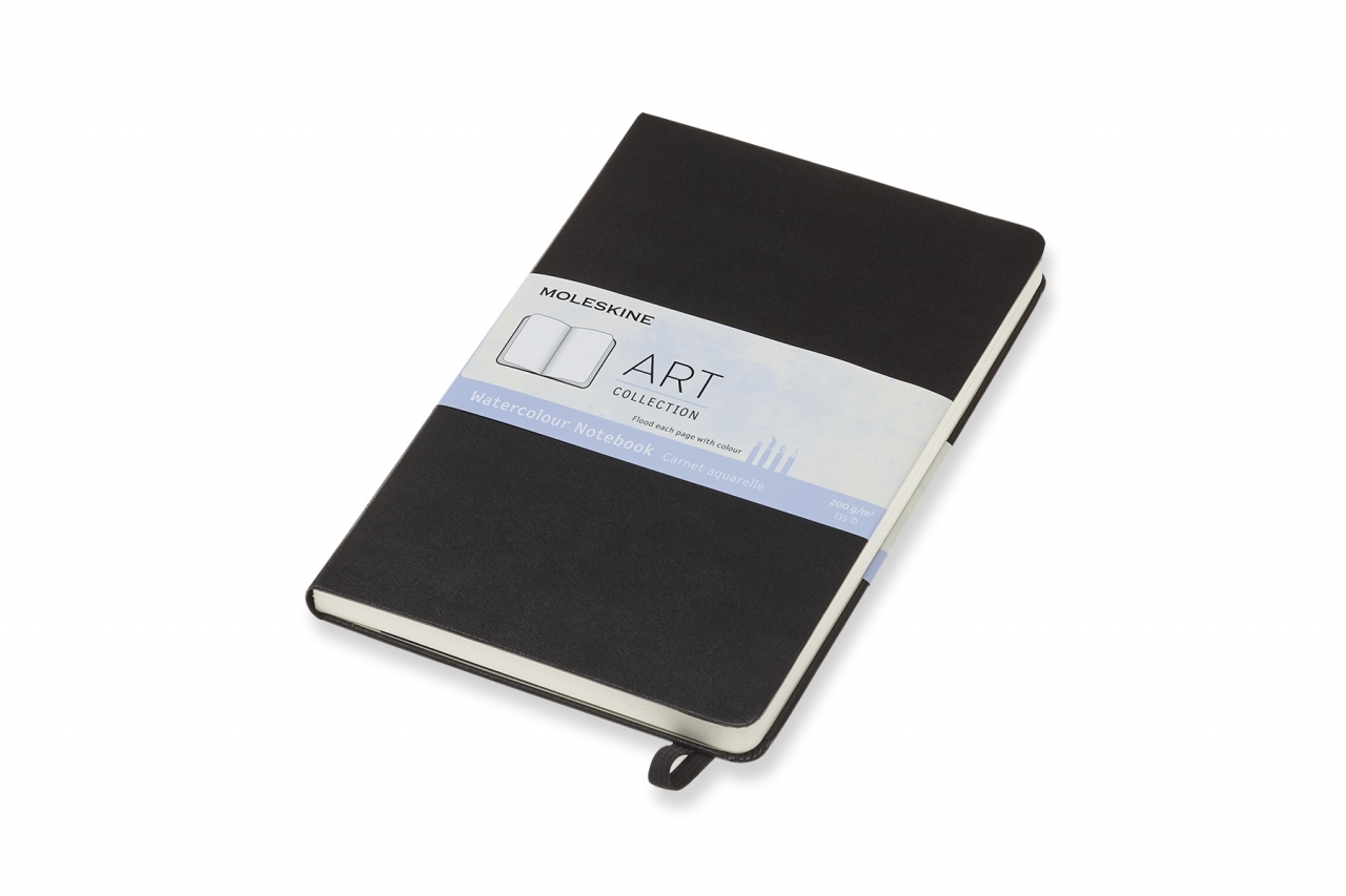 Juoda Moleskine akvarelės užrašų knygutė guli įstrižai, su Art Collection etikete, kreminių lapų bloku ir juodu skirtuku