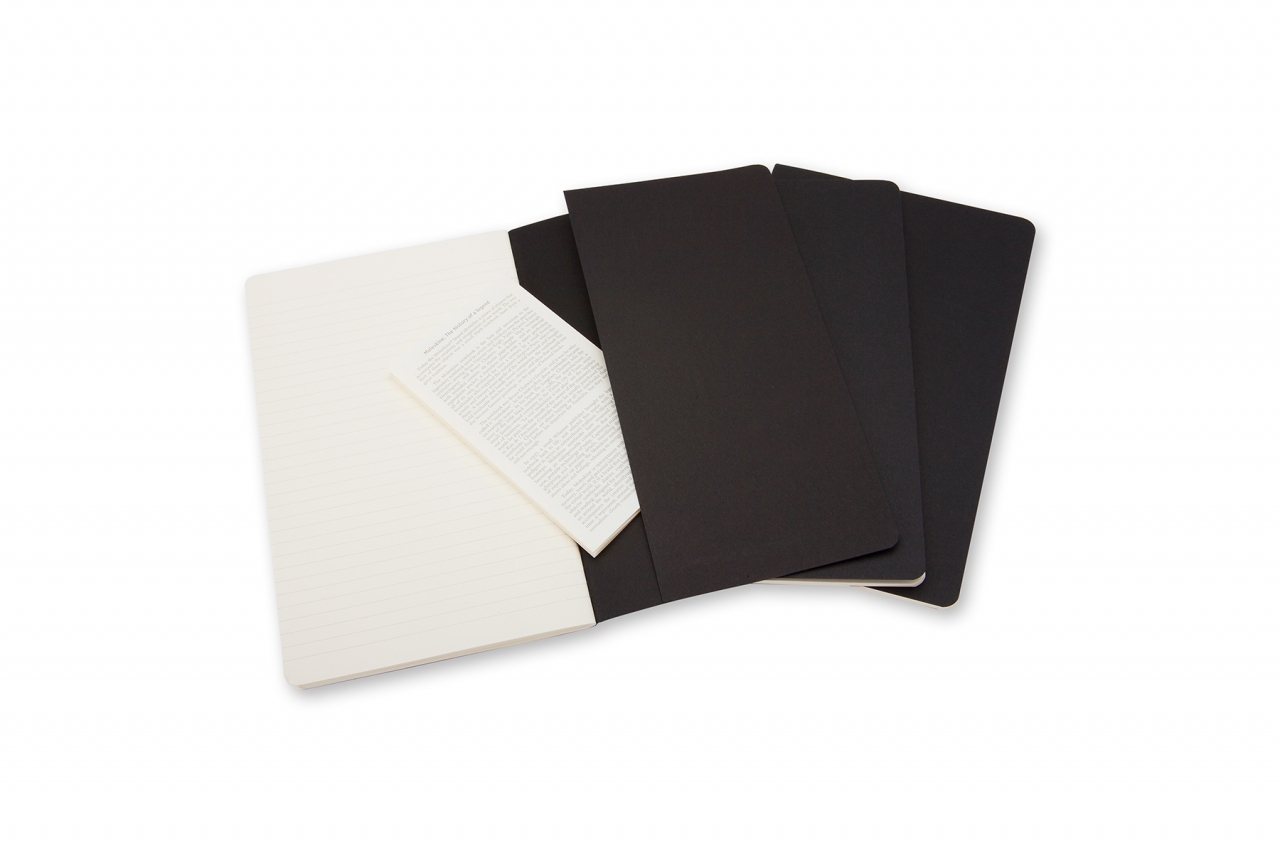 Atversta juoda Moleskine Cahier užrašinė su linijuotu puslapiu, vidine kišene, kreminiu lapeliu ir dviem sąsiuviniais fone