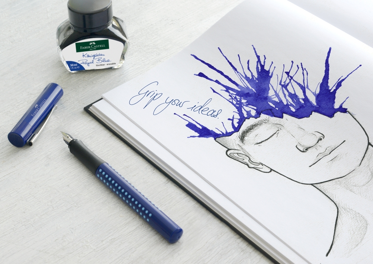 Atverstas albumas su veido eskizu ir mėlyno rašalo dėmėmis, šalia Faber-Castell buteliukas bei plunksnakotis