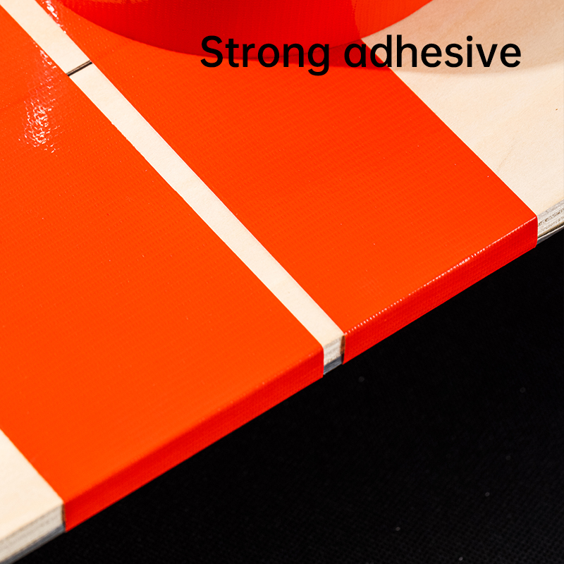 Blizgi raudona Deli juosta užklijuota per baltą siūlę ant šviesaus pagrindo su užrašu Strong adhesive viršuje