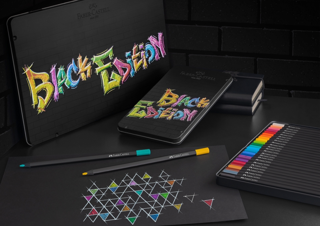 Black Edition pieštukų dėžutės, atvertas spalvų rinkinys ir geometrinis piešinys ant juodo popieriaus